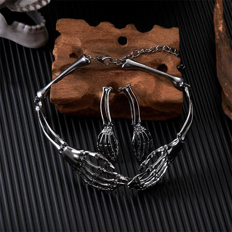 Silver alloy skull and ghost claw necklace with matching earrings set on a dark background.
