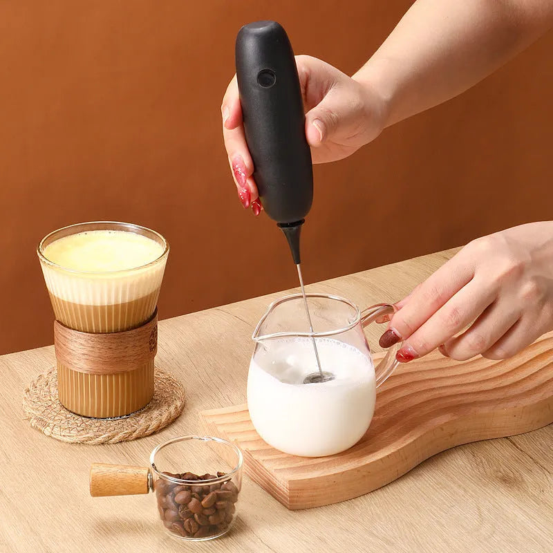 Black and white hand-held electric milk frother blender on kitchen counter