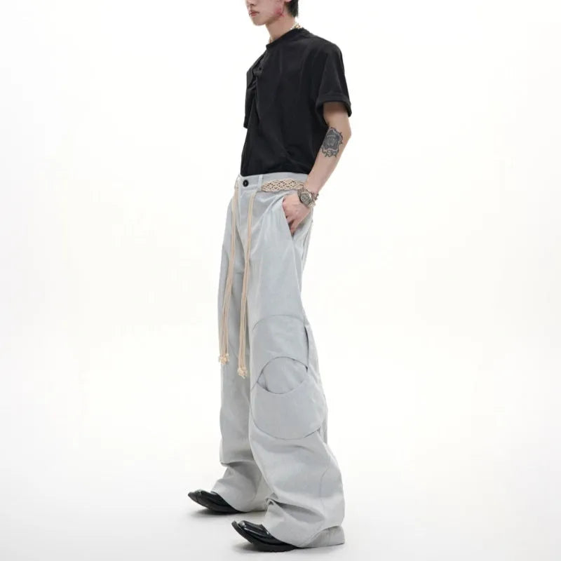 Men's dark coloured straight-leg jeans with heavy 3D cutting, belt-loop stitching, and decorative zipper details