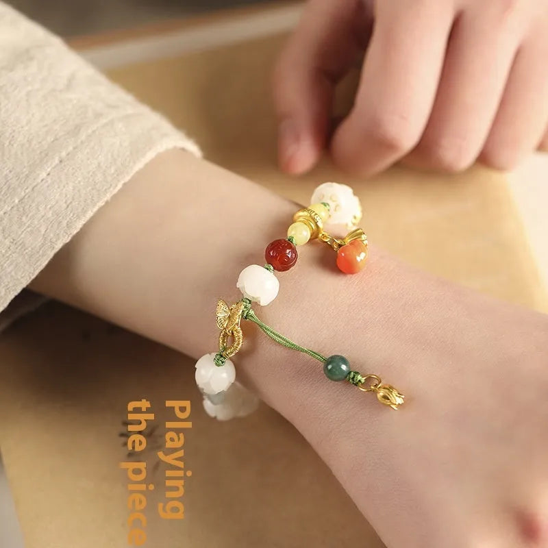 Close-up of a hand-woven white jade Bodhi bracelet with pumpkin and lotus beads on an adjustable rope.