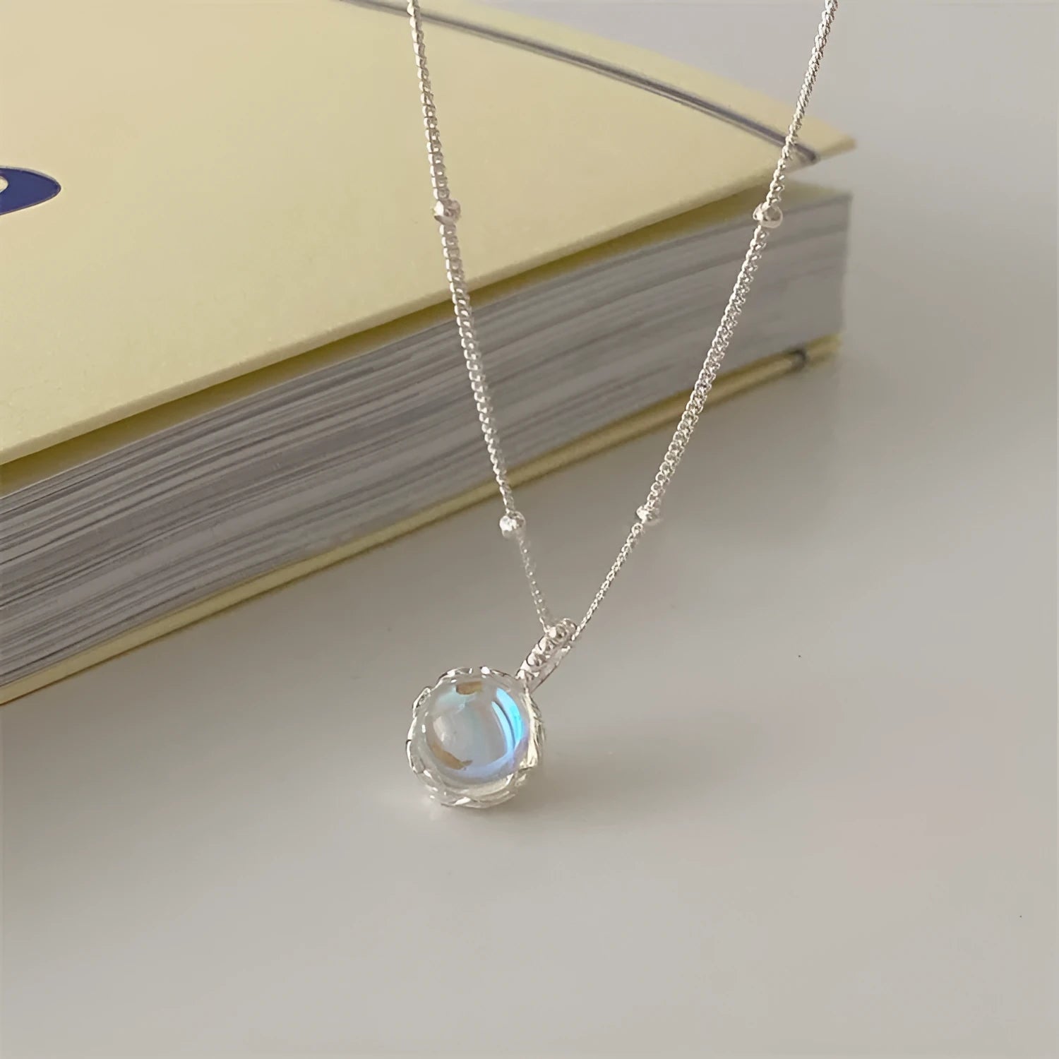 Silver necklace with geometric stone pendant on an adjustable curb chain.