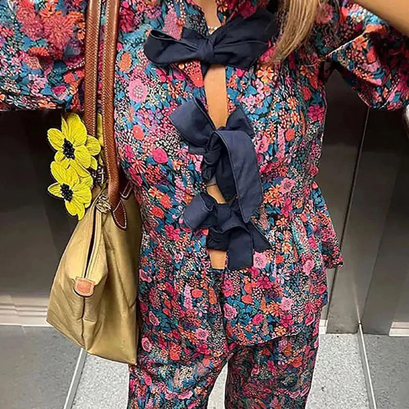 Women's floral printed trousers suit with tie-neck puff sleeve top and matching trousers in polyester fabric