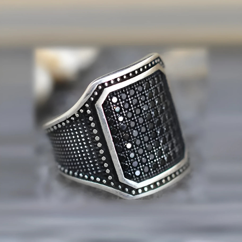 Black alloy ring with copper inlay detail and a single cubic zirconia stone.