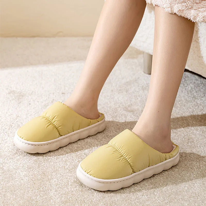 A pair of thick-soled house slippers with an artificial leather upper and plush lining, shown in a choice of colours.