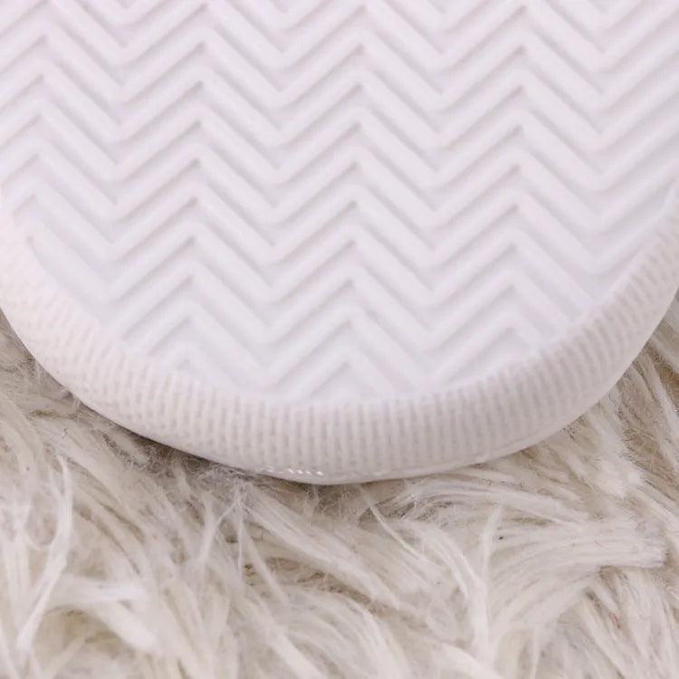 White fluffy slippers with cartoon pattern, rubber sole, and a toe holder design.