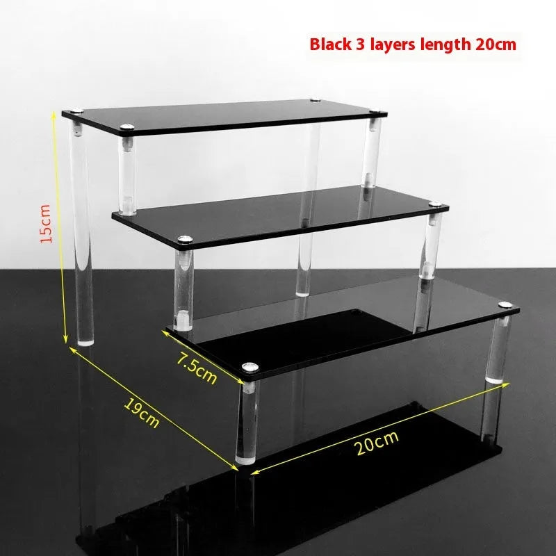 Transparent acrylic ladder display rack with three trapezoidal tiers showing blind box figurines on a desk