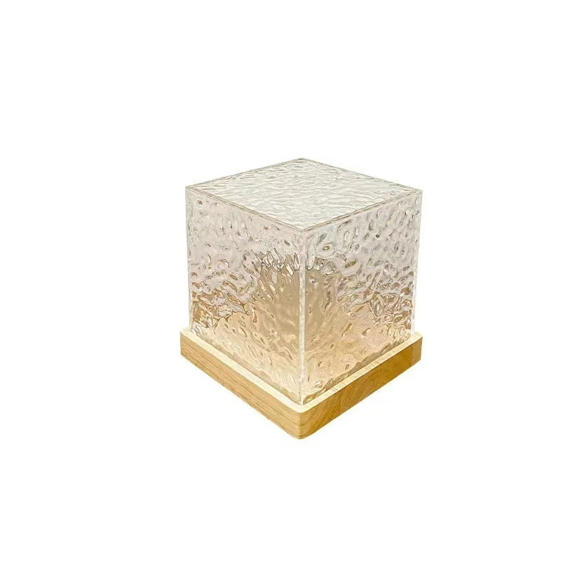 Modern geometric crystal table lamp projecting colourful water ripple light effect on wall.