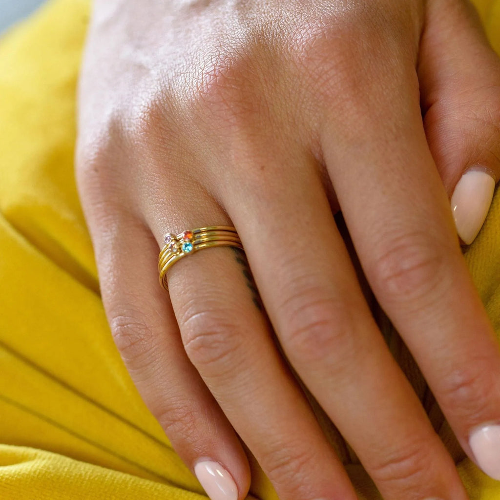 A geometric engraved titanium steel ring with a December birthstone, showcasing gold-tone and steel lettering accents.