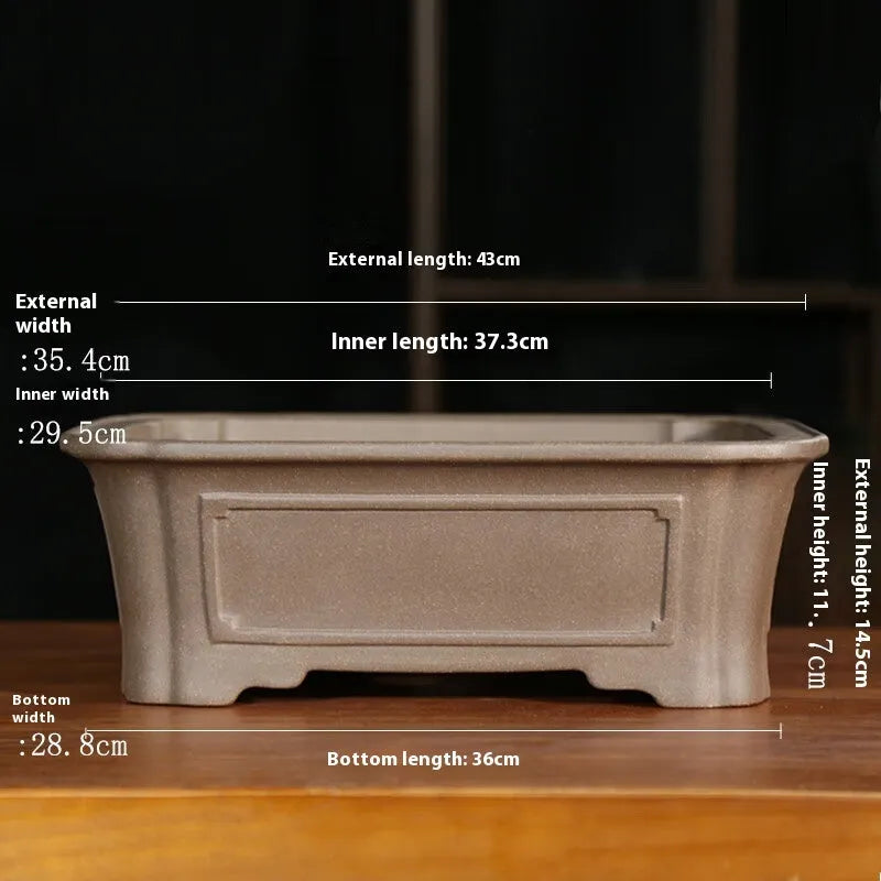 Classical rectangular purple sand bonsai pot with cut corners on a floor.