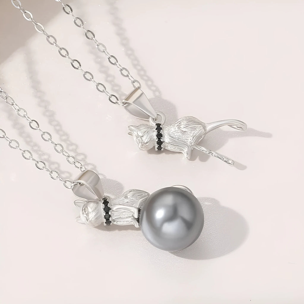Close-up of a delicate sterling silver cat pendant on a thin clavicle-length chain.