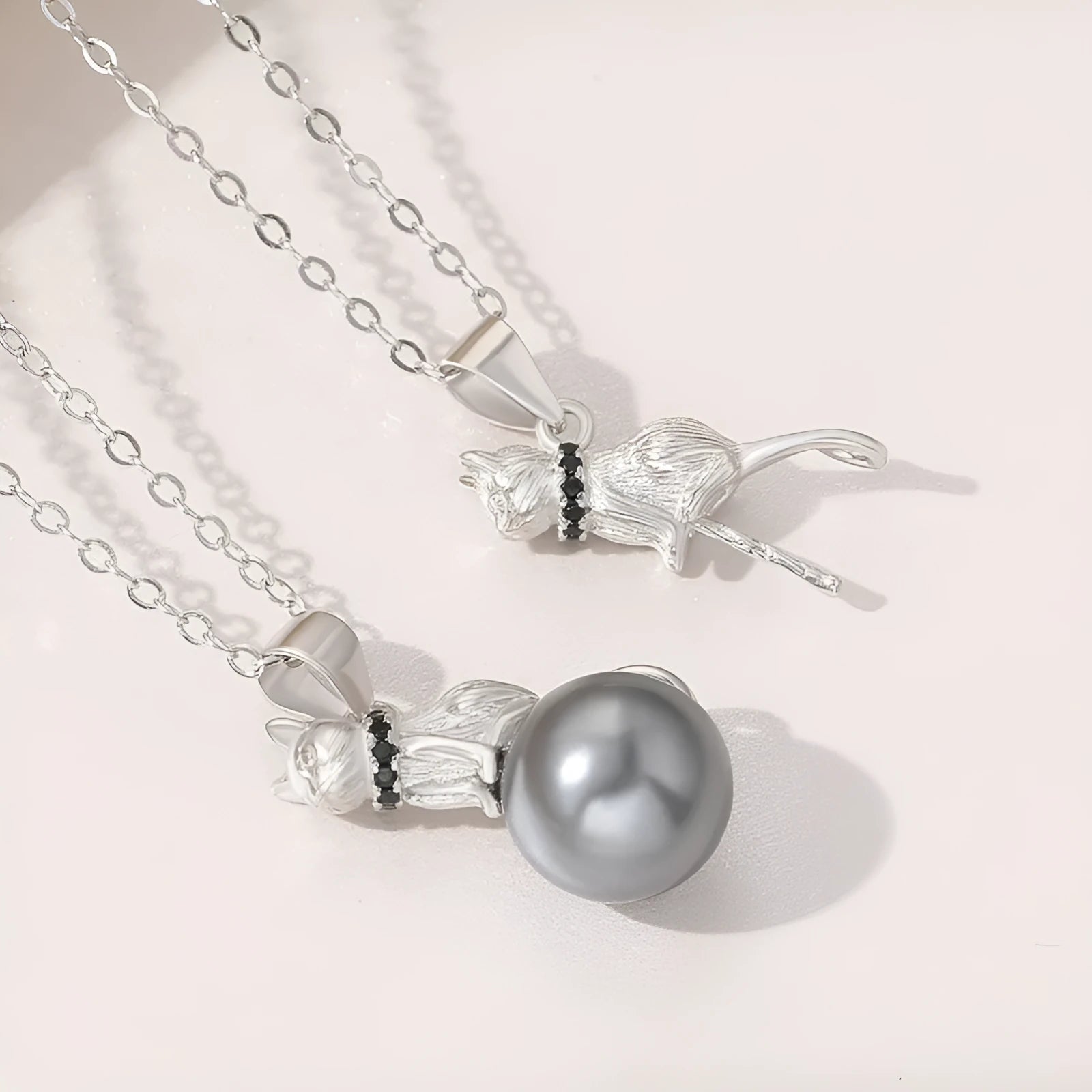 Close-up of a delicate sterling silver cat pendant on a thin clavicle-length chain.
