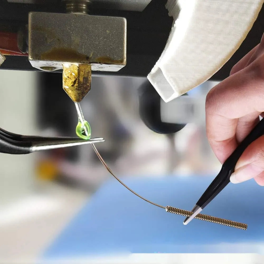 Brass MK8 3D printer nozzle and stainless steel cleaning pin on a white background.