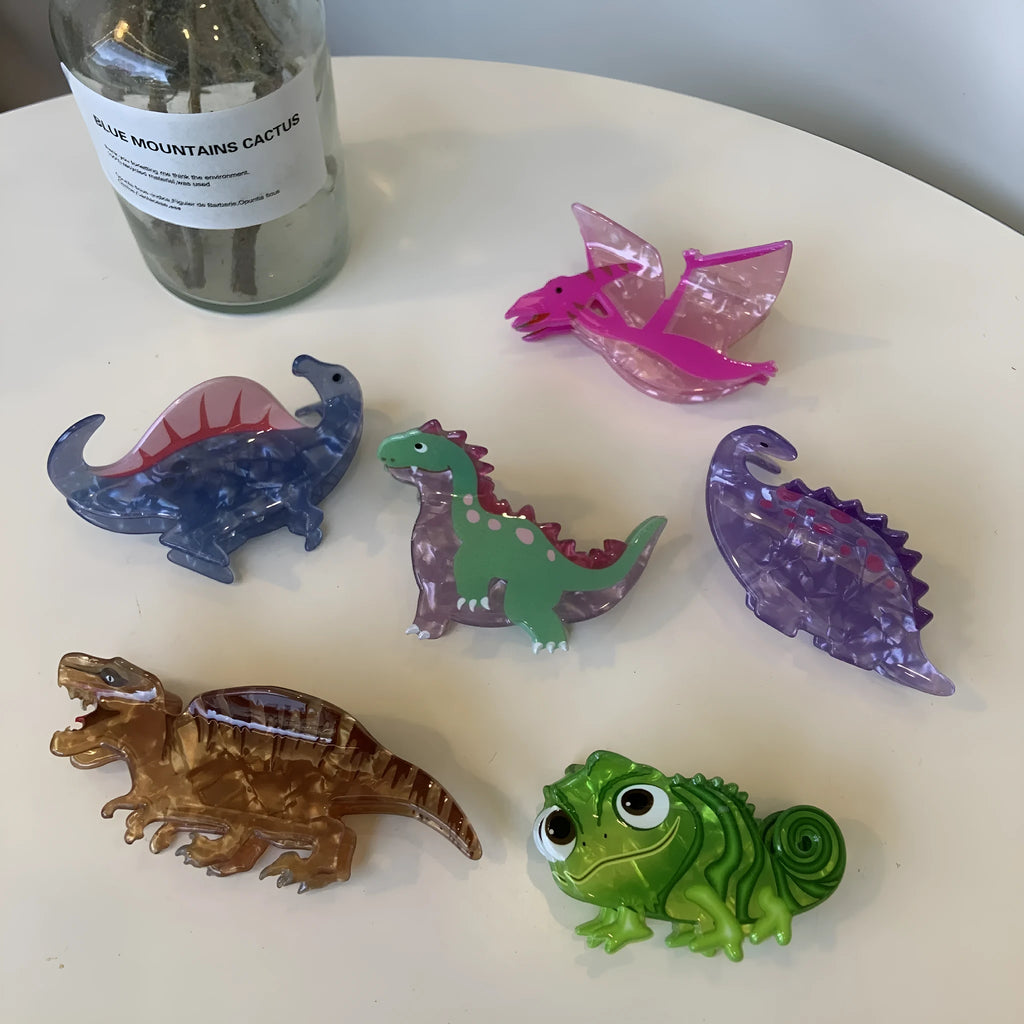 Dinosaur themed acrylic jaw hair clip showing six colour variations including pink, green, purple, blue and brown designs