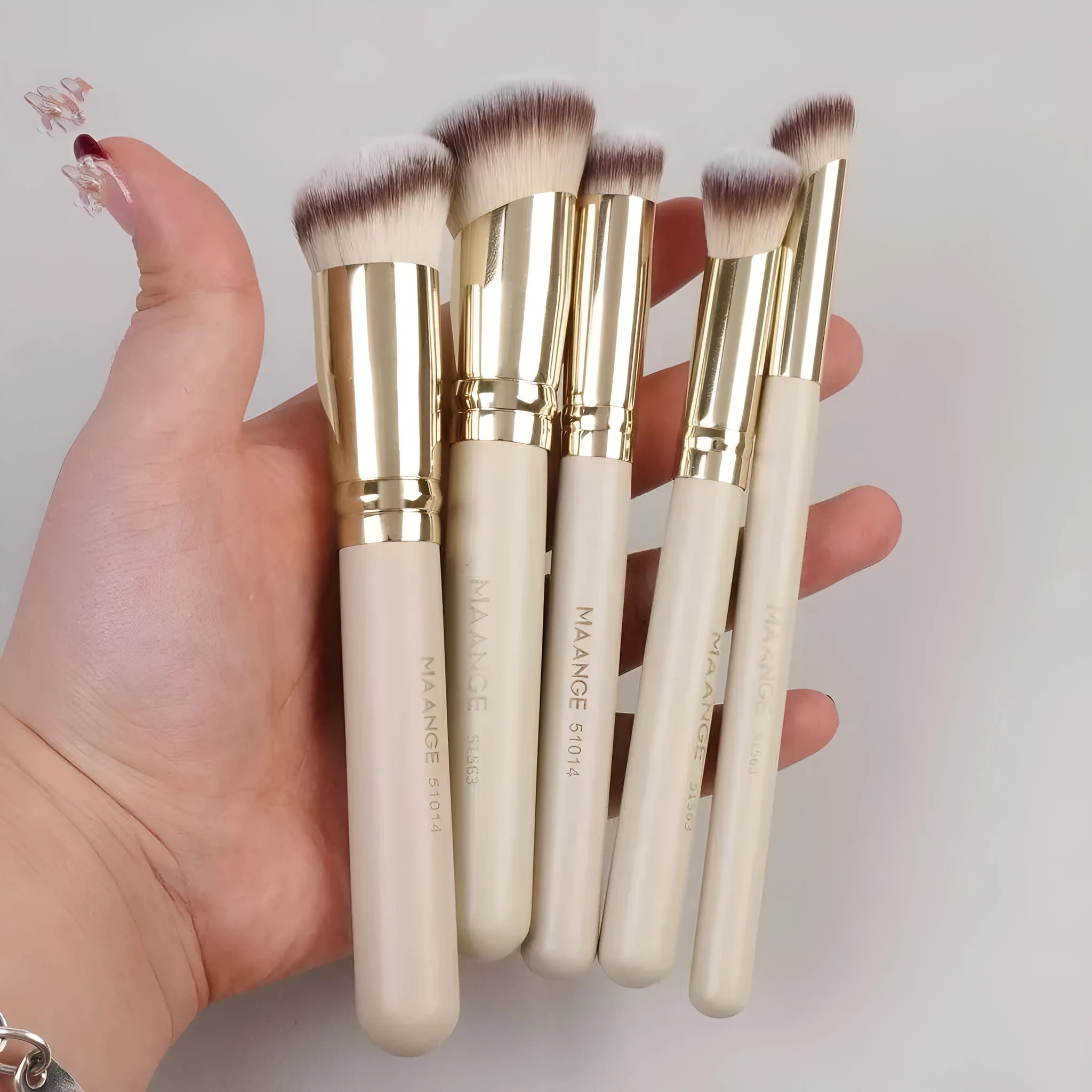 Five apricot coloured angled makeup brushes with synthetic bristles for foundation and powder application