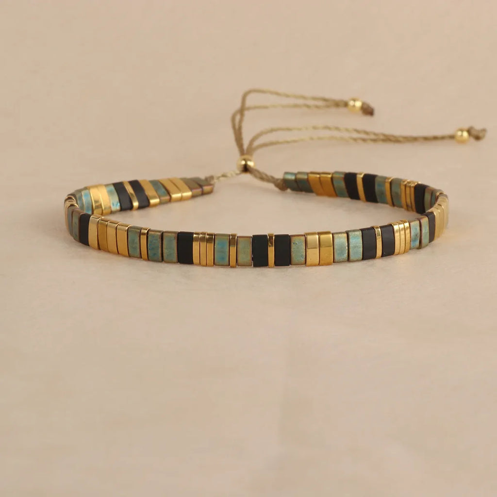 Geometric beaded bracelet with round elements in milky white, black, green, blue, or red.