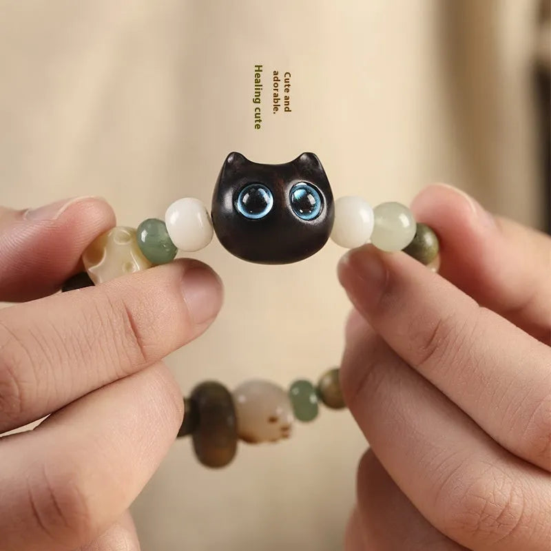 Hand-woven Buddhist bracelet with jade beads, wood elements, and cat's paw charm in rosewood or ebony with yellow or blue eyes