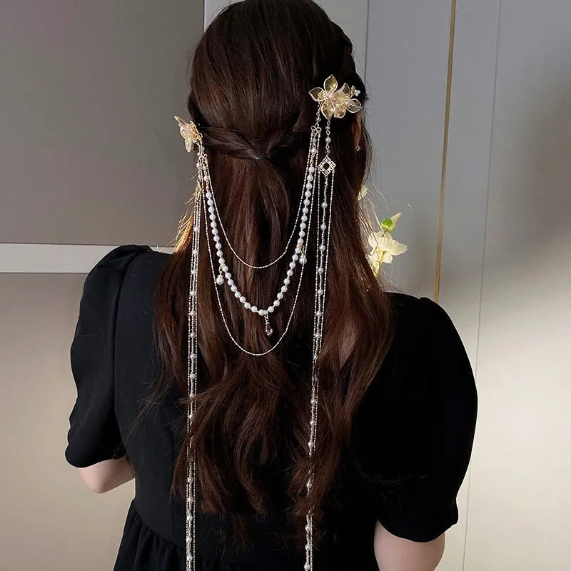 Gold acrylic women's hairpin with white flower, pearl beads, diamond accents, and a long black tassel.