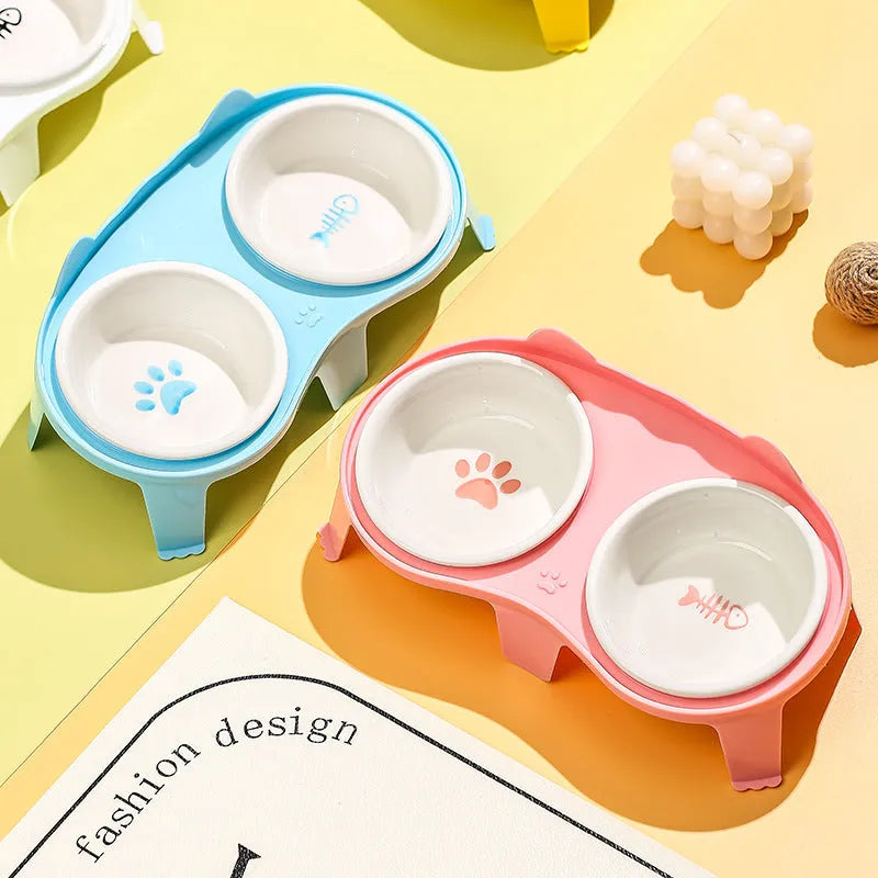 Blue ceramic cat food and water bowls on a white elevated plastic stand with hook design.