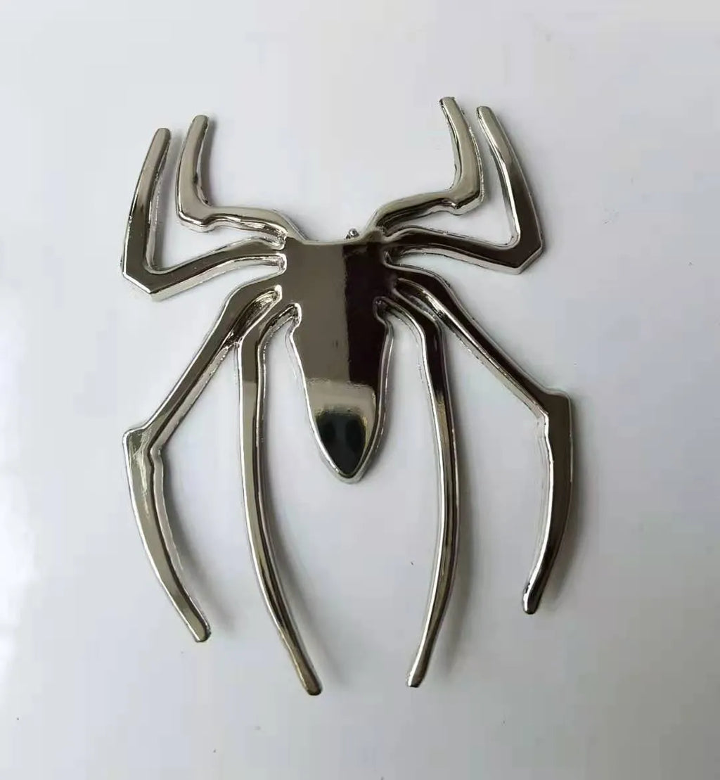 Three-dimensional metal spider bumper sticker in zinc alloy, shown in gold colour, measuring 7 by 5 cm.