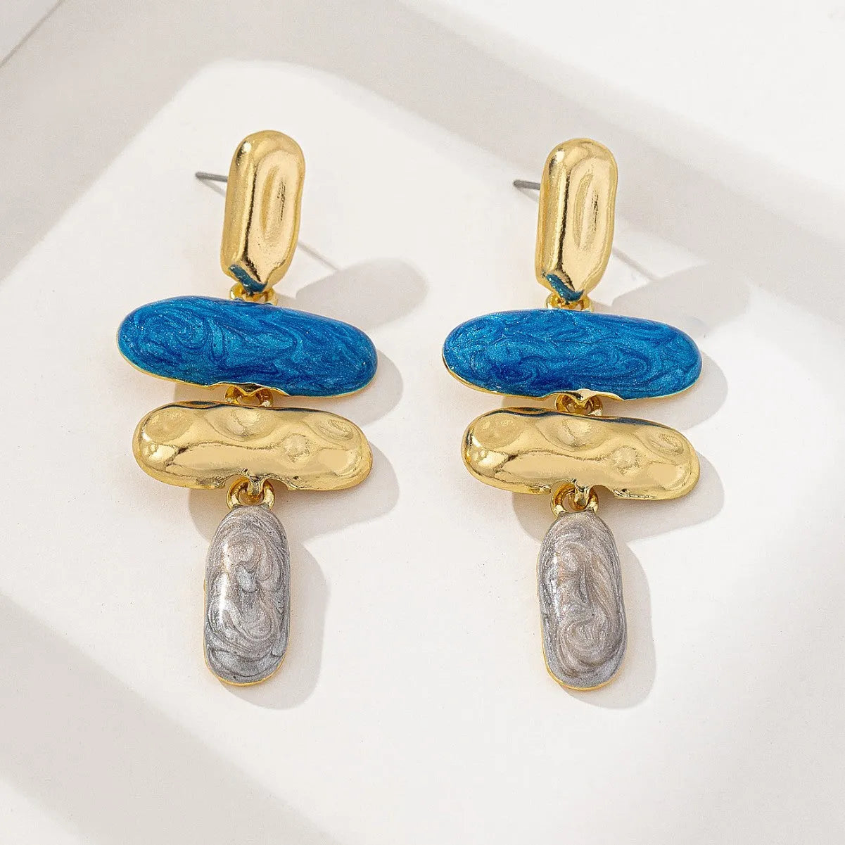A pair of geometric-shaped stud earrings with a multicolour electroplated metal finish.