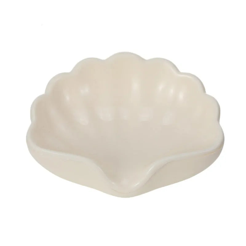 White or pink plastic shell-shaped soap dish for bathroom countertop or shower storage.
