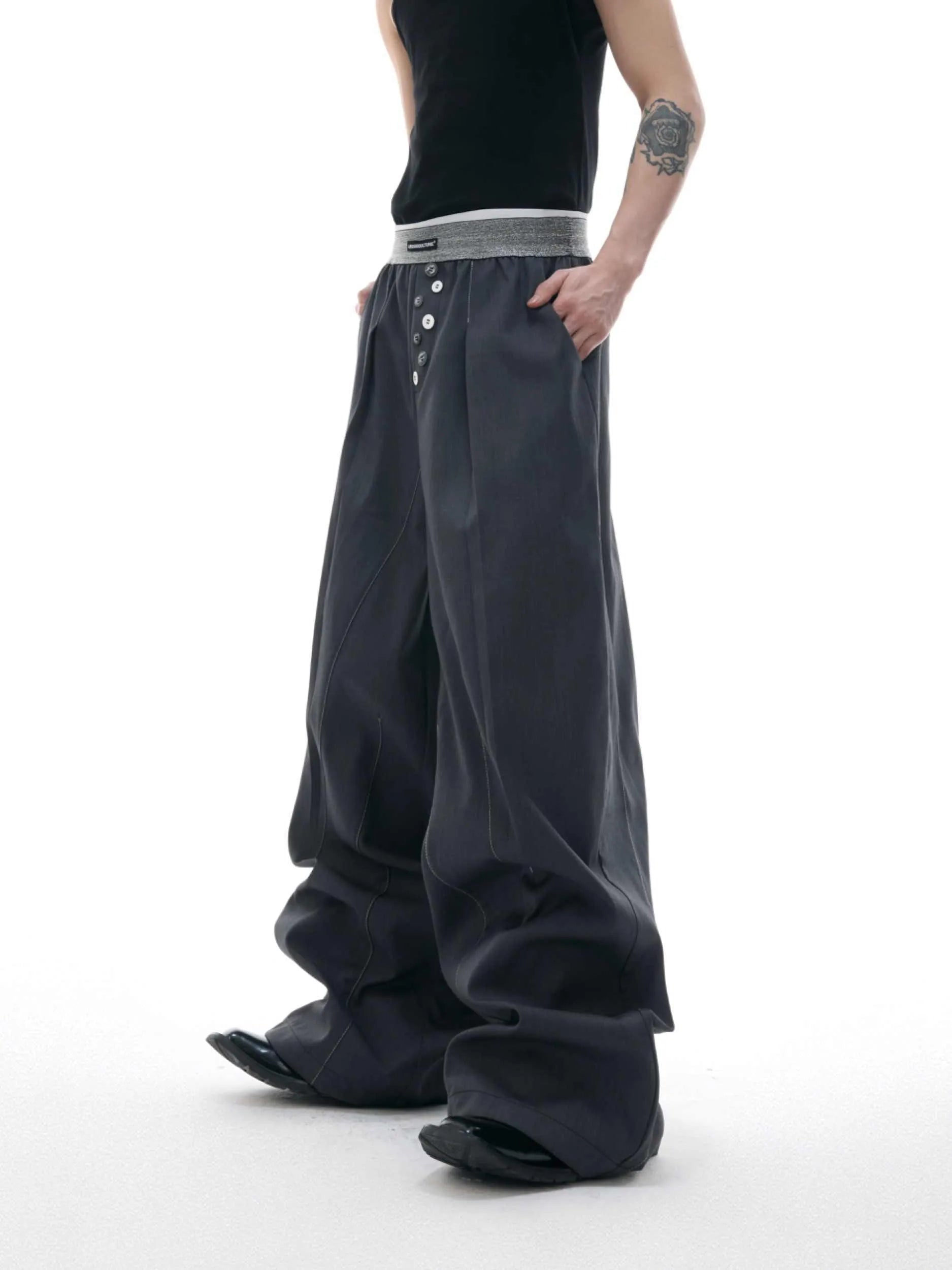 Men's black drooping straight-leg suit trousers with high waist and button detail.