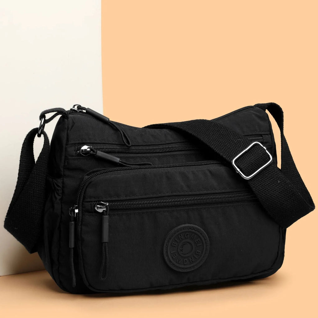 Water-repellent nylon crossbody bag with three-dimensional pockets in grey, black or red options