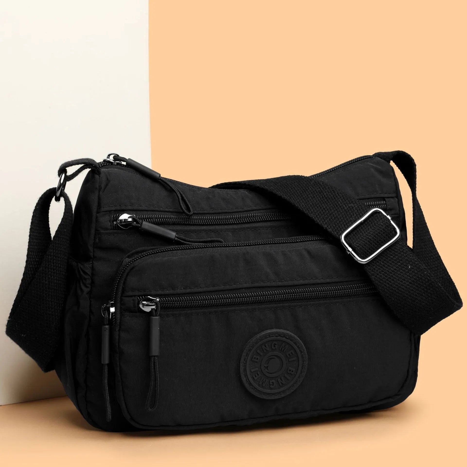 Water-repellent nylon crossbody bag with three-dimensional pockets in grey, black or red options