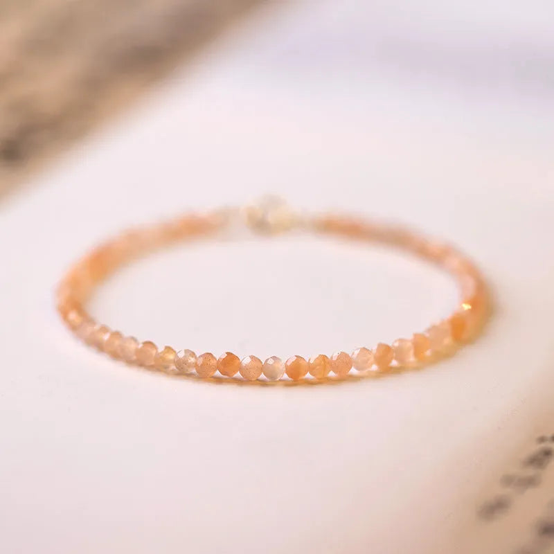 Close-up of a women's bracelet with small 3mm round sunstone beads on a string.
