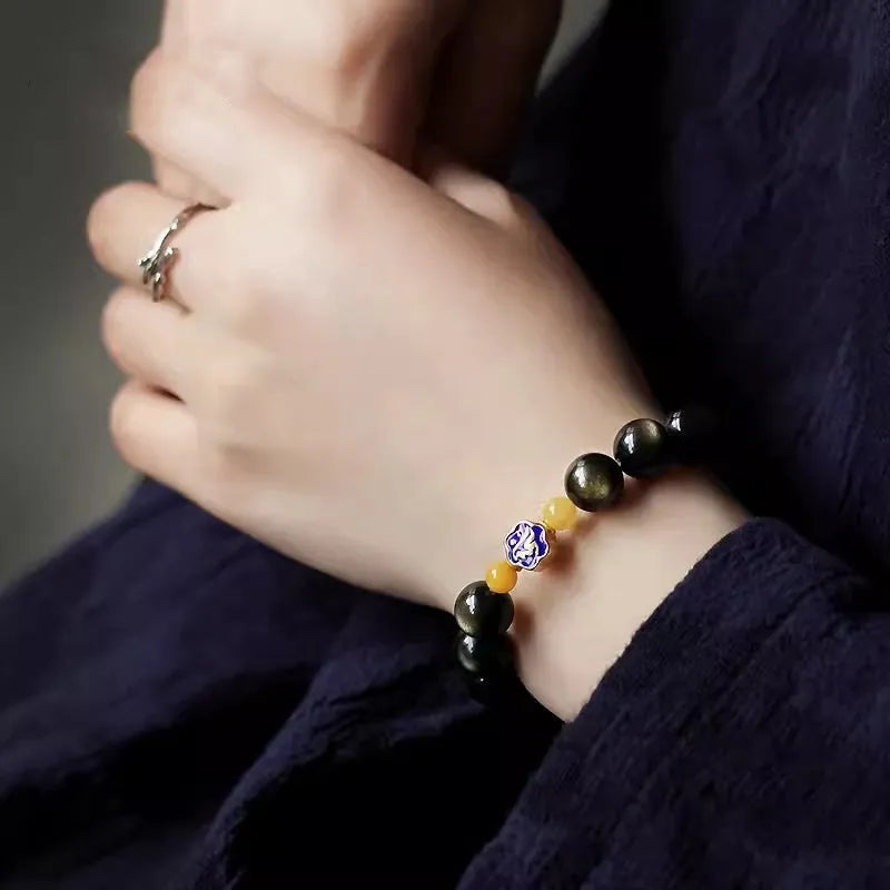 Handmade golden obsidian bracelet with 10mm geometric beads on a wrist, showing ethnic zodiac design.