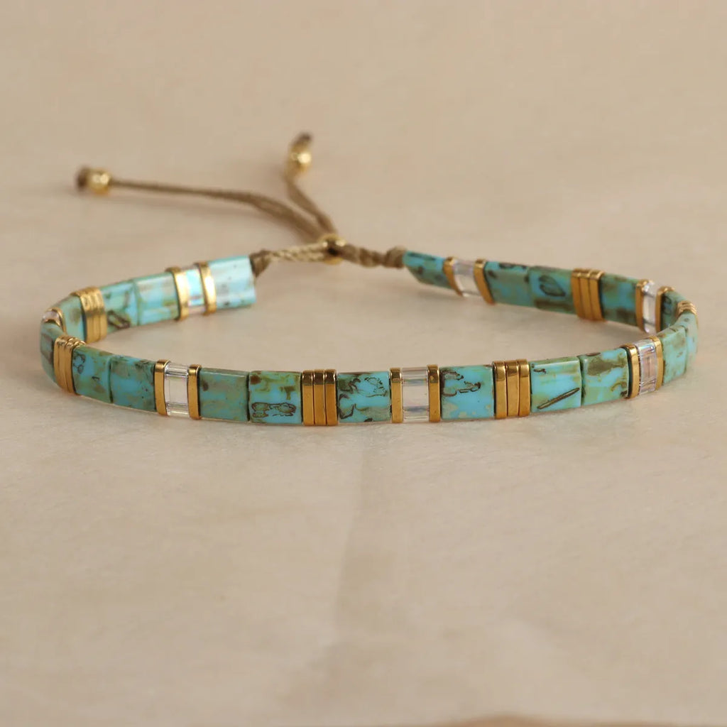 Geometric beaded bracelet with round elements in milky white, black, green, blue, or red.
