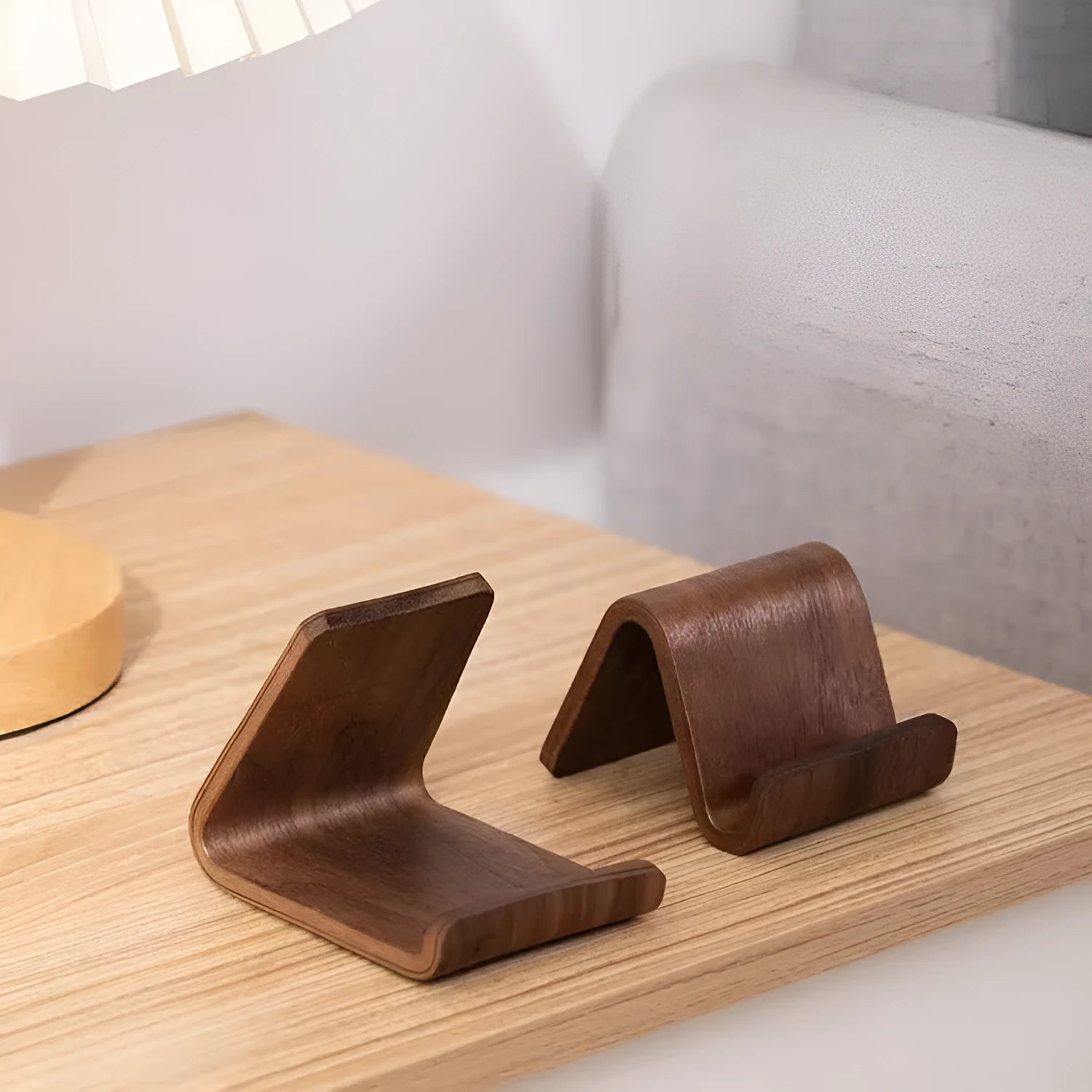 Walnut wood mobile phone bracket holding a smartphone on a wooden desk