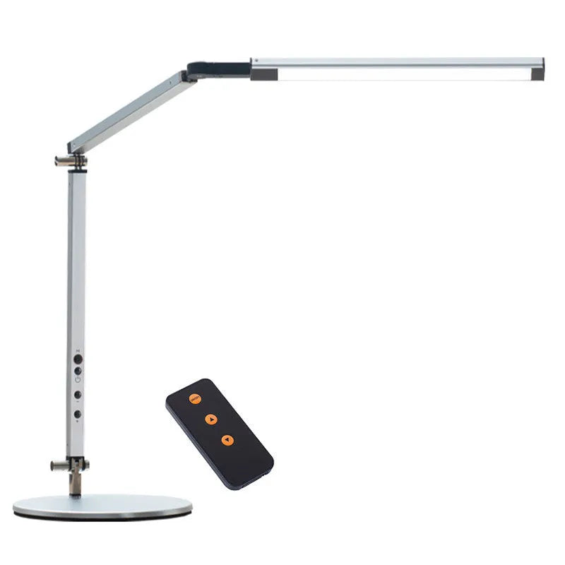 Aluminium clip-on desk lamp with adjustable arm and remote control on a wooden desk.