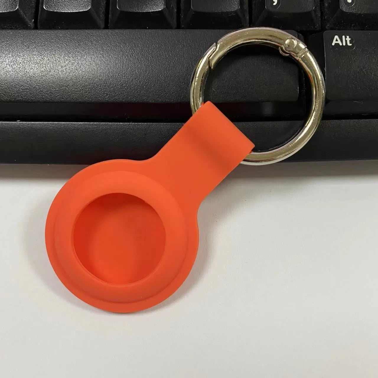 Silicone protective case for Apple AirTag with metal snap button in assorted colours on a keyring.