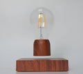 Magnetic levitation light bulb floating above wood-effect base with international plug adapters