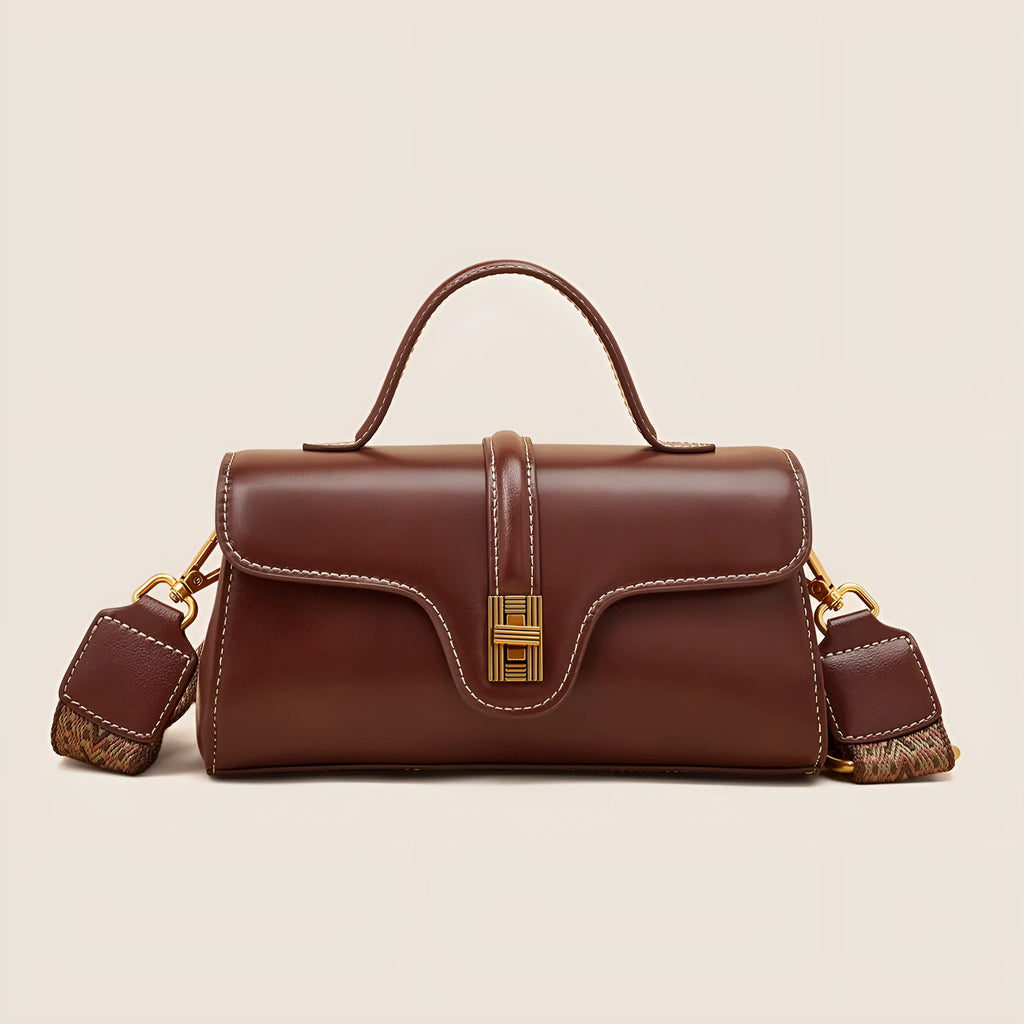 Brown Cambridge-style crossbody messenger bag with clamshell opening and lock detail on a table.
