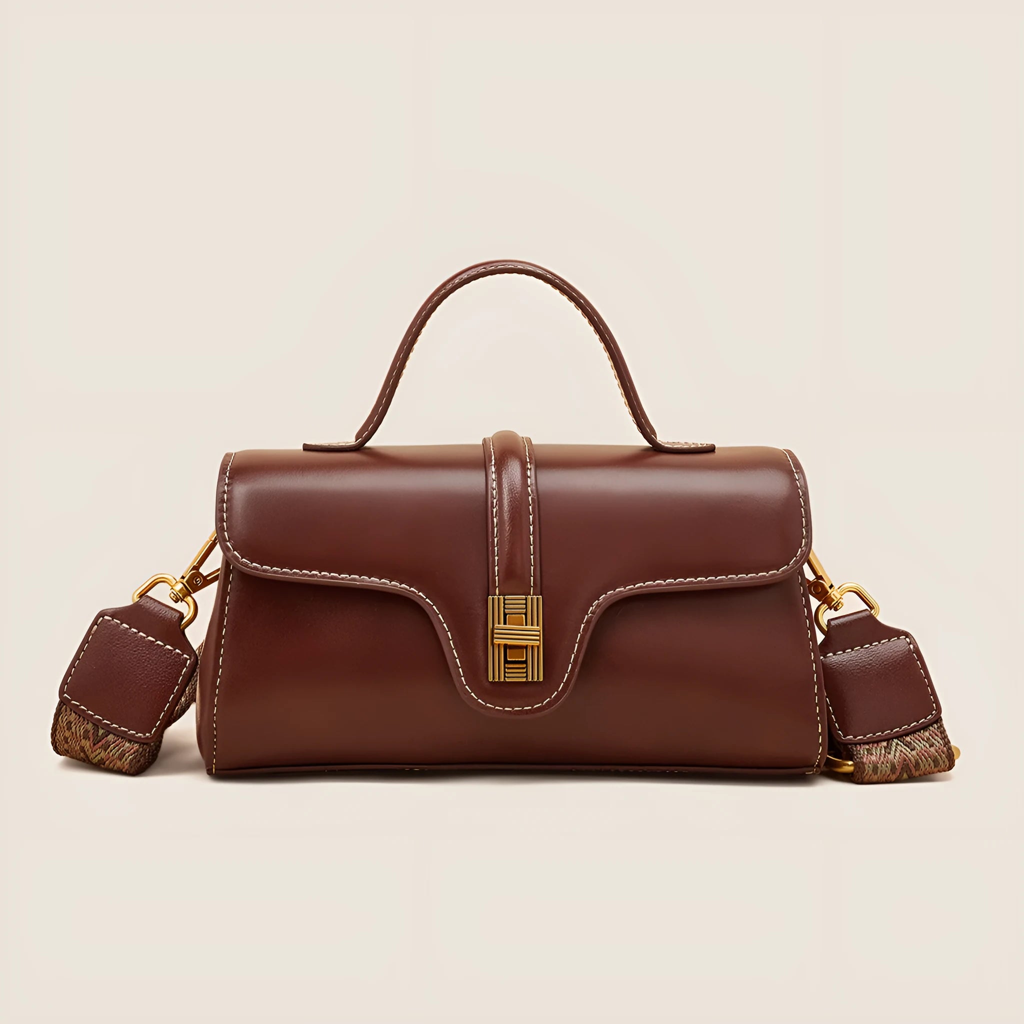 Brown Cambridge-style crossbody messenger bag with clamshell opening and lock detail on a table.