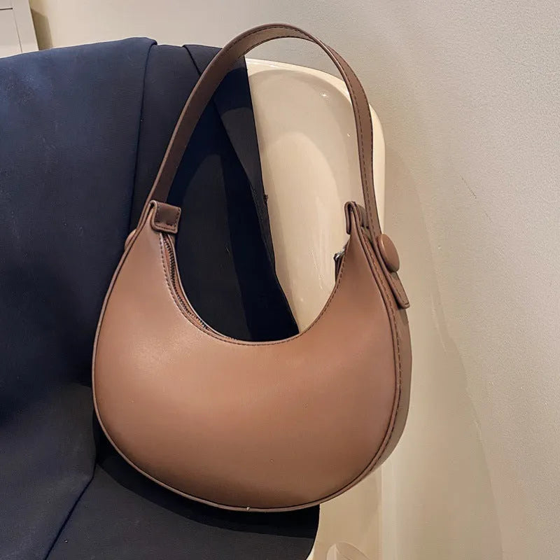 Retro dumpling-shaped black PU leather women's shoulder bag with a front sandwich pocket.