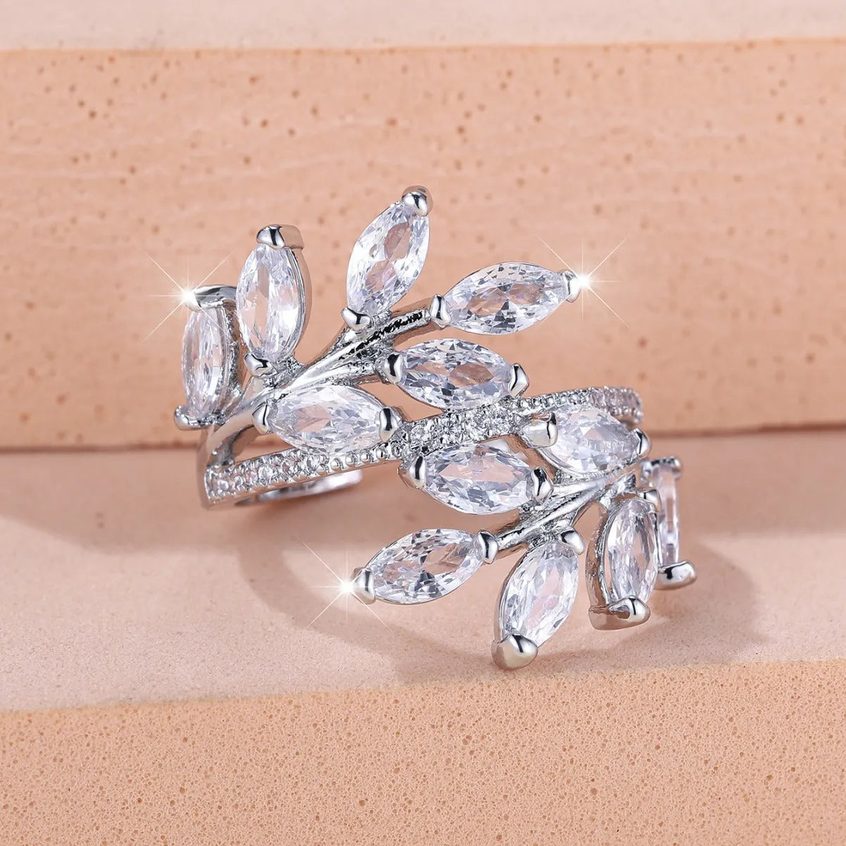 Adjustable copper leaf-shaped ring with zircon stones in various colour options on a white background.