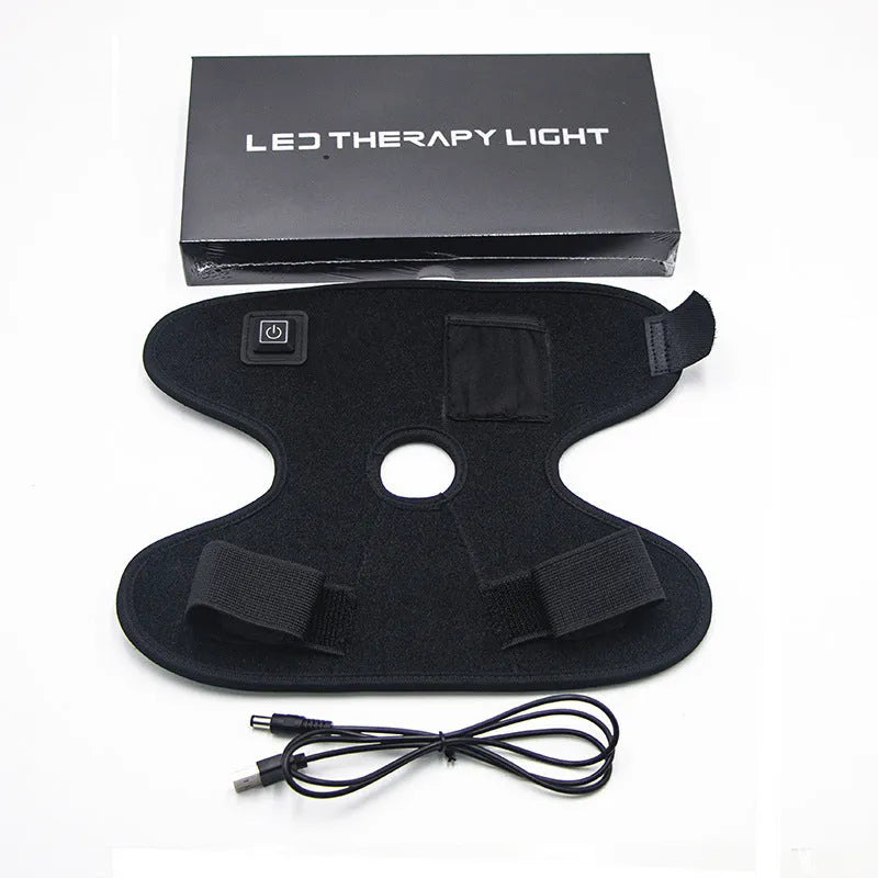 Black fabric ankle support with red light and heating therapy, USB cable, on a flat surface