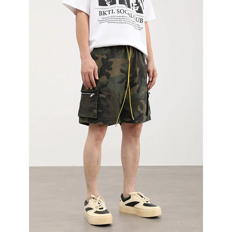 Men's camouflage multi-pocket cropped work shorts laid flat showing cargo pockets and camo pattern.