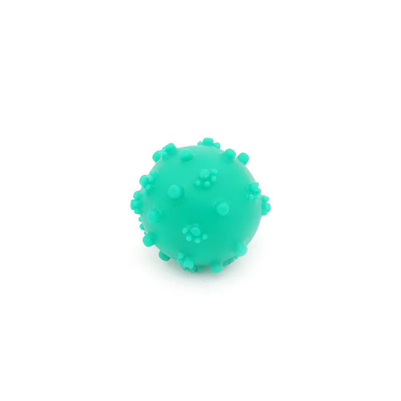 Blue, green, pink, and yellow spiky dog toy balls with paw print dimples, shown next to a small dog.