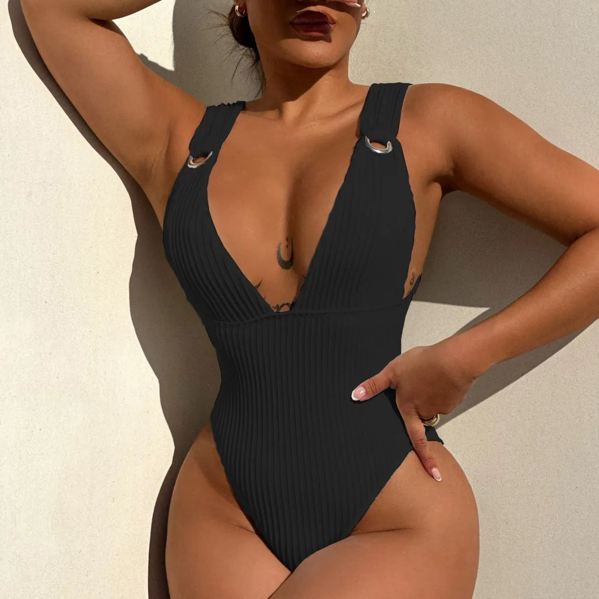 Women's solid colour one-piece swimsuit on a hanger in black, white, green, and orange.