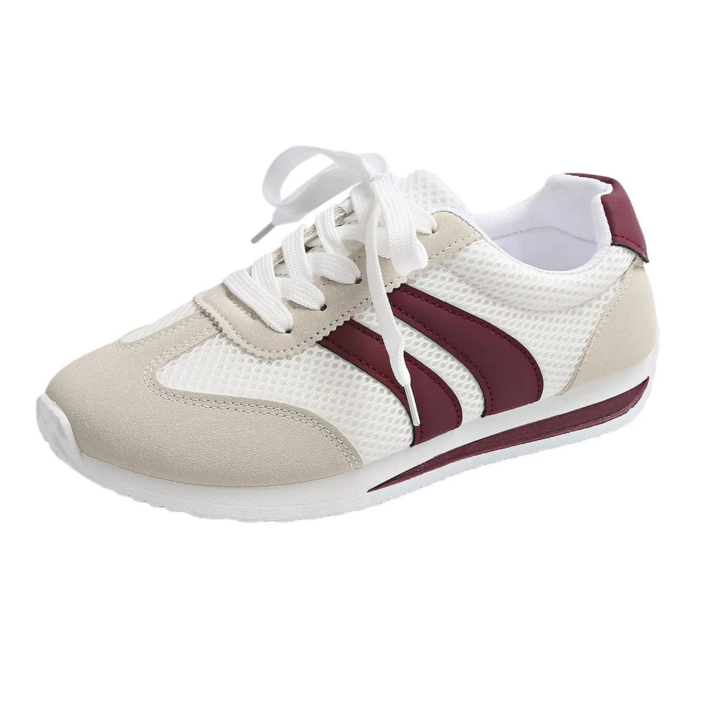 Wine red women's low-top sneaker with mesh upper, synthetic leather accents, and elastic cross straps on a flat rubber sole.