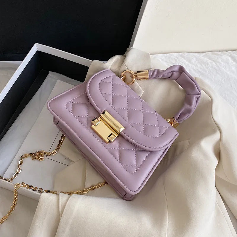 Purple rhombus-shaped women's shoulder bag with a chain strap on a white background.