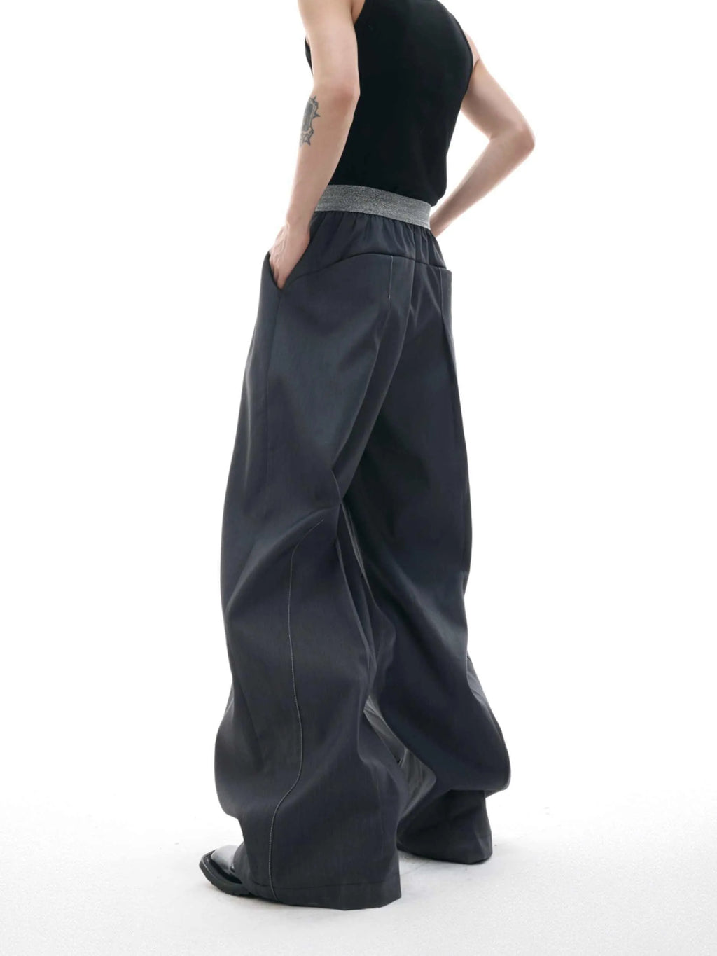 Men's black drooping straight-leg suit trousers with high waist and button detail.