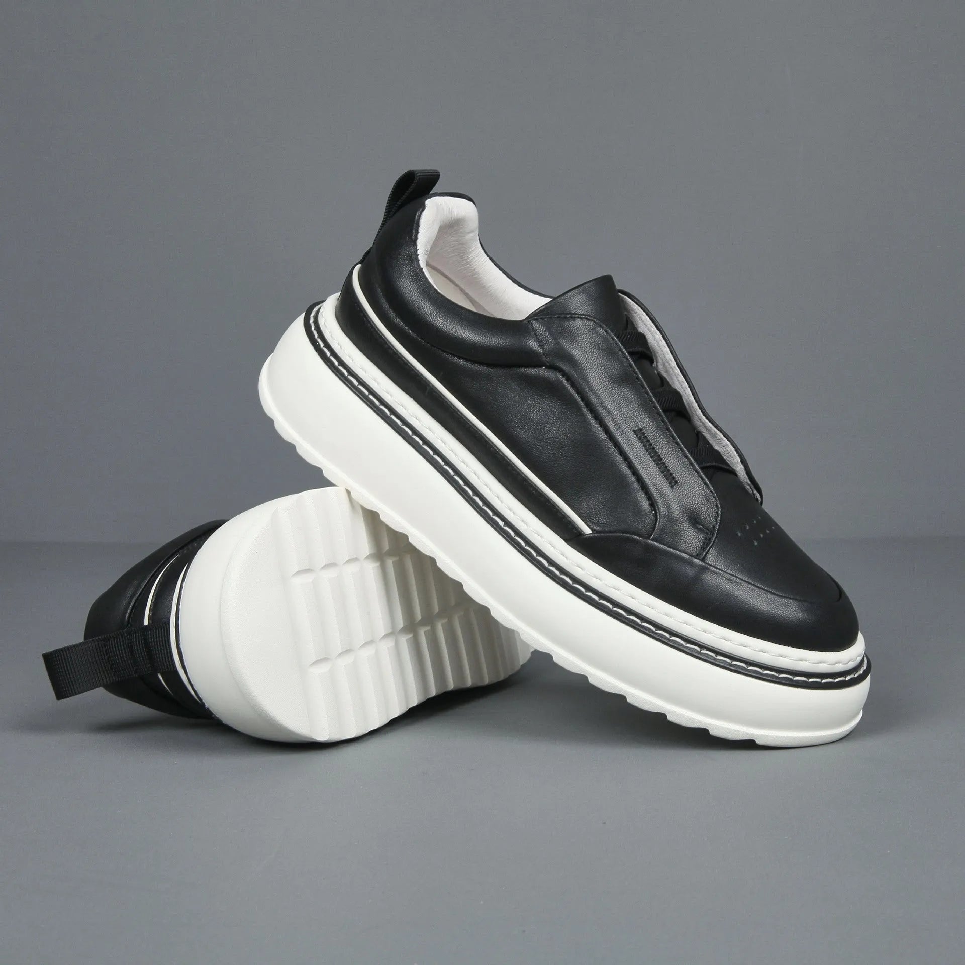 Black casual slip-on sneaker with leather upper, foam platform sole, and elastic band – side view