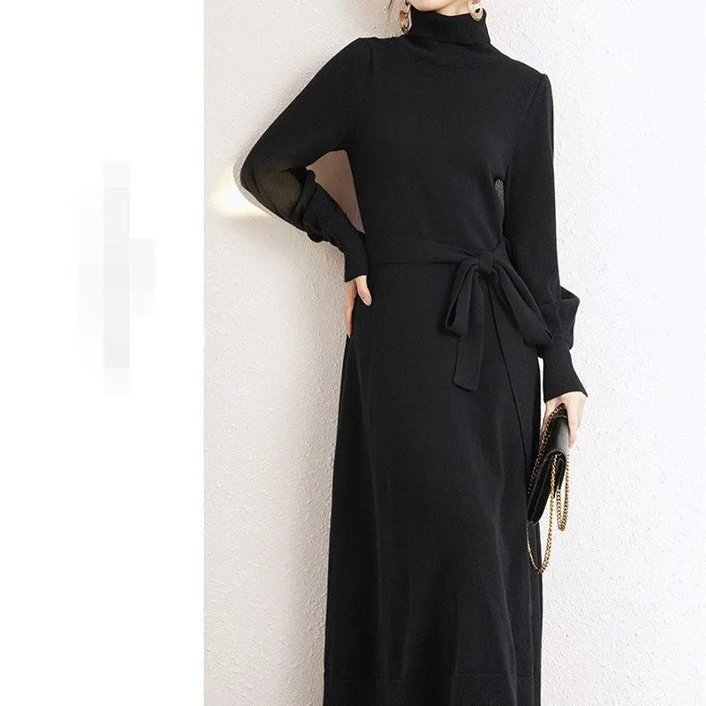 Adult woman wearing a rose red loose-knit turtleneck sweater dress with a flared midi skirt and elastic waist.