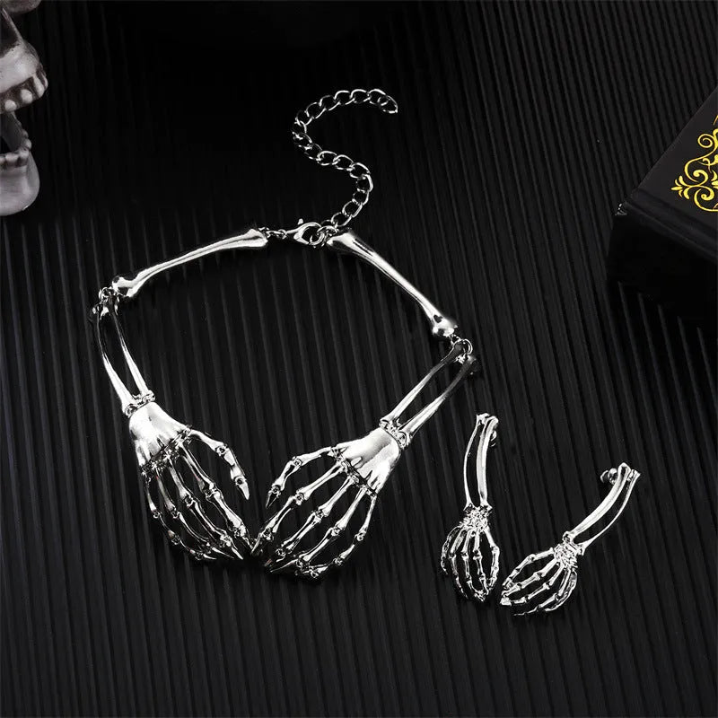 Silver alloy skull and ghost claw necklace with matching earrings set on a dark background.