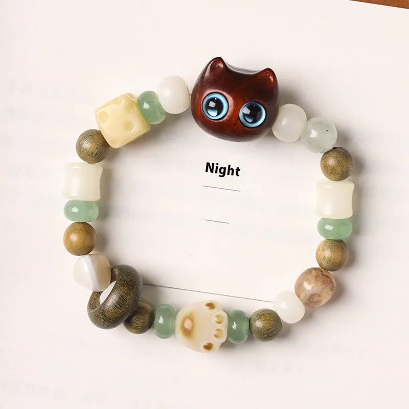 Hand-woven Buddhist bracelet with jade beads, wood elements, and cat's paw charm in rosewood or ebony with yellow or blue eyes